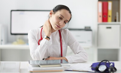 Tired doctor with cervical pain at his desk. Irregular working hours in the medical field concept