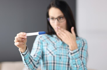 Surprised woman holding pregnancy test in her hand. Pregnancy test after missed period concept