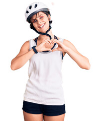 Beautiful young woman with short hair wearing bike helmet smiling in love showing heart symbol and shape with hands. romantic concept.