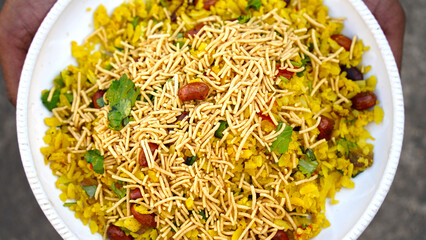 indian breakfast dish poha.Indian breakfast Poha topped with peanuts, pomegranate seeds, chopped green chilly, onion, lime, coriander leaves and curry leaves.