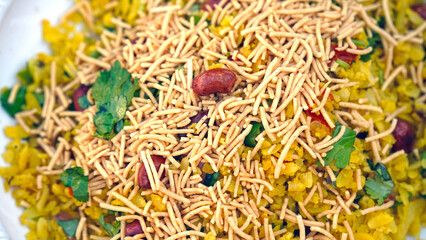 indian breakfast dish poha.Indian breakfast Poha topped with peanuts, pomegranate seeds, chopped green chilly, onion, lime, coriander leaves and curry leaves.