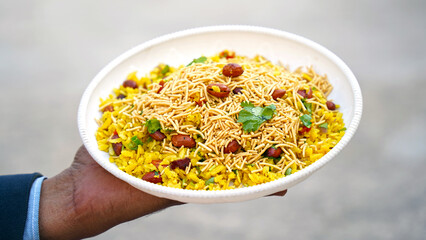 indian breakfast dish poha.Indian breakfast Poha topped with peanuts, pomegranate seeds, chopped green chilly, onion, lime, coriander leaves and curry leaves.