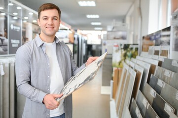 Male customer choosing kitchen ceramic tile in store - obrazy, fototapety, plakaty