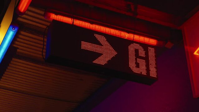 Red LED sign displaying the word girls with arrow outside strip club, close-up