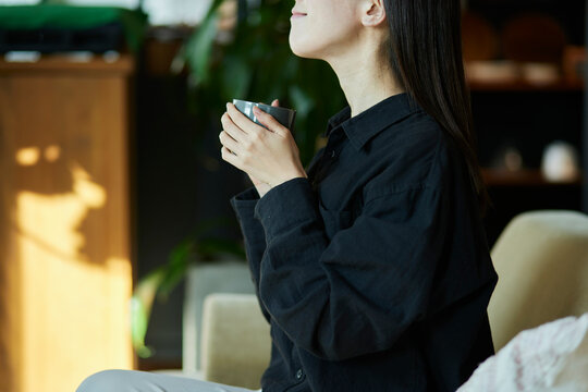 リビングでマグカップを持ってくつろぐ日本人の女性