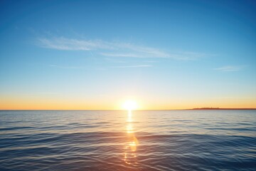Obraz premium sunrise over calm ocean with clear blue sky