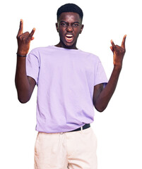 Fototapeta premium Young african american man wearing casual clothes shouting with crazy expression doing rock symbol with hands up. music star. heavy concept.