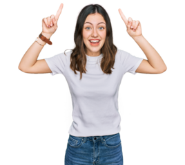 Young beautiful woman wearing casual white t shirt smiling amazed and surprised and pointing up with fingers and raised arms.