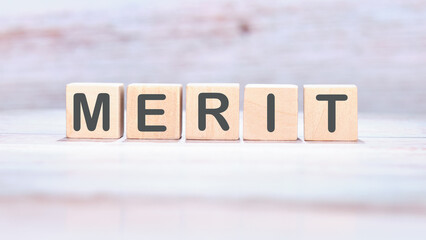 Merit word made of wooden cubes on a light background