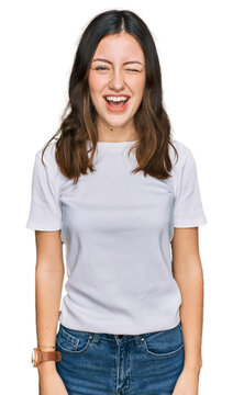 Young beautiful woman wearing casual white t shirt winking looking at the camera with sexy expression, cheerful and happy face.