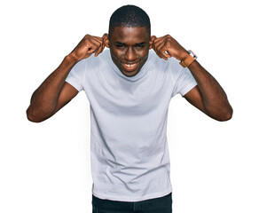 Young african american man wearing casual white t shirt smiling pulling ears with fingers, funny...