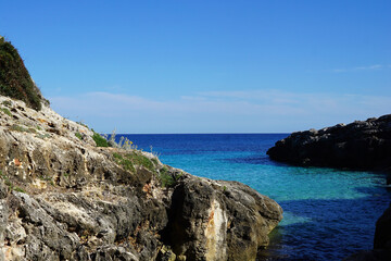 Natural landscape of Playa de Cavalleria (Mercadal) in Minorca beach with clear blue sky and rocky seashore- Menorca, Spain
