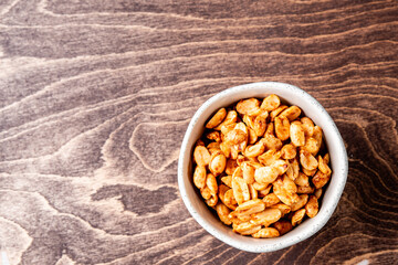 Roasted peanuts and salt in a bowl on a wooden background