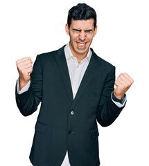 Handsome hispanic man wearing business clothes very happy and excited doing winner gesture with arms raised, smiling and screaming for success. celebration concept.