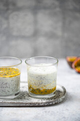 Chia pudding with passion fruit puree and yogurt in a glass on a grey background. Healthy vegetarian food. Tasty breakfast idea. Parfait with tropical fruit.