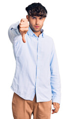 Young hispanic man wearing casual shirt looking unhappy and angry showing rejection and negative with thumbs down gesture. bad expression.