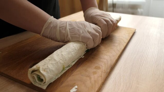 We wrap pita bread, forming a roll. Preparation of a roll with cheese, fish and vegetables