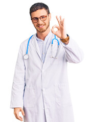 Handsome young man with bear wearing doctor uniform smiling positive doing ok sign with hand and fingers. successful expression.