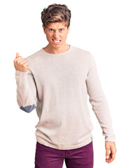 Young handsome man wearing casual clothes angry and mad raising fist frustrated and furious while shouting with anger. rage and aggressive concept.