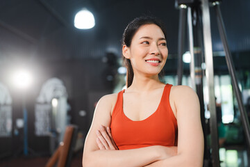 A smart and confidence healthy sporty female is standing arms crossed with inspiration and motivation look in gym, health club or fitness center. Muscular or body build, healthy lifestyle backgrounds.