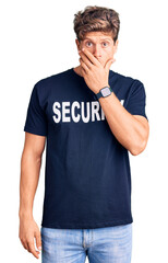 Young handsome man wearing security t shirt shocked covering mouth with hands for mistake. secret concept.