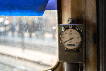 An analog speedmeter with odometer (travel distance) recording of the old train which is installed in the driver cabin cockpit. Transportation equipment object photo, close-up.