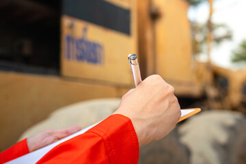 Action of an engineer hand is writing to perform inspection of the road roller or road compactor...