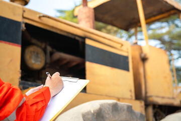 Action of an engineer hand is writing to perform inspection of the road roller or road compactor...