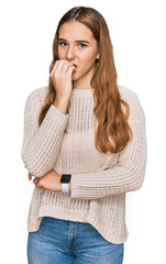 Young blonde woman wearing casual clothes looking stressed and nervous with hands on mouth biting nails. anxiety problem.