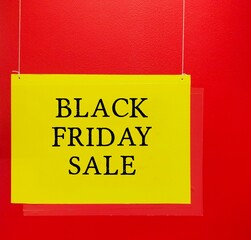 Yellow store sign BLACK FRIDAY SALE on red wall - where stores offer highly promoted sales at discounted prices - start of the Christmas shopping season in USA
