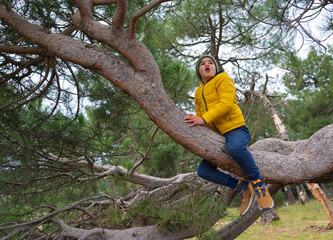 Boy climbing a tree with warm clothes and expression of surprise