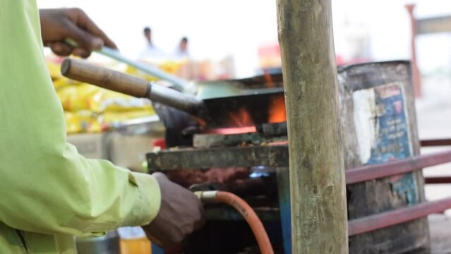 Man Making Hot and Spicy Noodles on Street.  Flame and Fring pan at work 