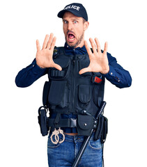 Young handsome man wearing police uniform afraid and terrified with fear expression stop gesture with hands, shouting in shock. panic concept.