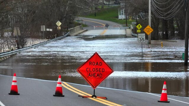 Road closed ahead sign with flooded bridge after heavy rainfall in USA. Natural disaster theme. Static aerial.