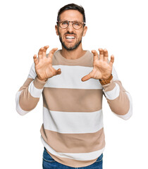 Handsome man with beard wearing casual clothes and glasses smiling funny doing claw gesture as cat,...