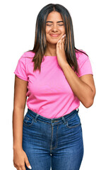 Obraz premium Young latin girl wearing casual clothes touching mouth with hand with painful expression because of toothache or dental illness on teeth. dentist