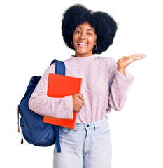 Young african american girl wearing student backpack holding book celebrating victory with happy...