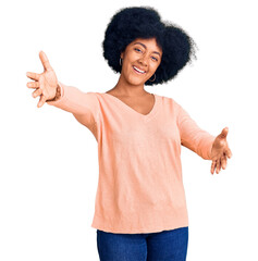 Young african american girl wearing casual clothes looking at the camera smiling with open arms for hug. cheerful expression embracing happiness.