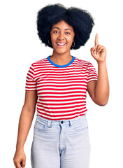 Young african american girl wearing casual clothes pointing finger up with successful idea. exited and happy. number one.