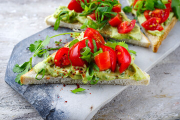 Traditionelles Toast Dreieck Sandwich mit Tomaten, Avocado Aufstrich und Kräuter serviert als...