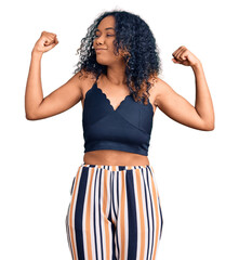 Young african american woman wearing casual clothes showing arms muscles smiling proud. fitness concept.