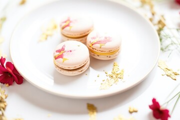 Fototapeta na wymiar raspberry macarons with edible gold leaf accents on white plate