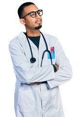 Fototapeta premium Young african american man wearing doctor uniform and stethoscope looking to the side with arms crossed convinced and confident