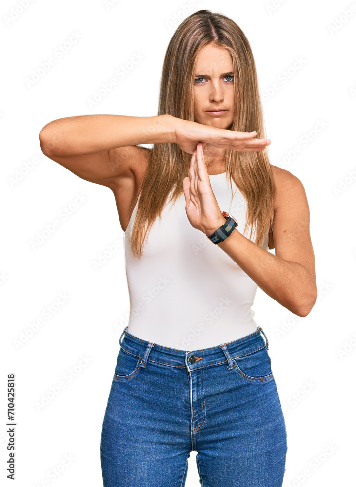 Wall mural Young blonde woman wearing casual style with sleeveless shirt doing time out gesture with hands, frustrated and serious face