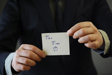 Businessman in a suit hand holding sticker with tax time