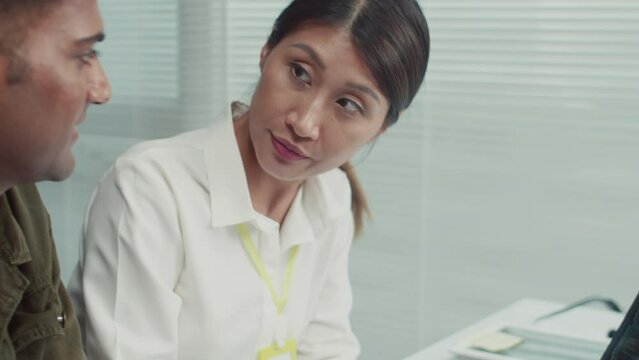 Tilt up shot of female technician and male client checking work of smartphone together using special app on laptopTilt up shot of female technician and male client checking work of smartphone together