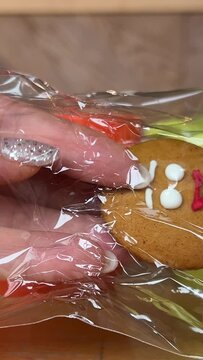 gingerbread man Gift for Christmas delicious cookies take out from packaging dance beautiful toy delicacy female hands with shiny Christmas manicure Present yami. symbol of winter New Year