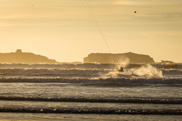 Silhouette of kitesurfer on the beach with reflection at sunset in background. Essaouira, Morocco