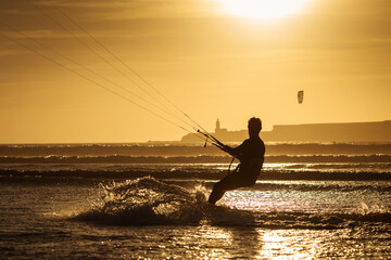 Silhouette of kitesurfer on the beach with reflection at sunset in background. Essaouira, Morocco