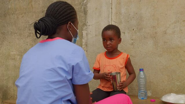 young cute nice little black children kid of Africa is taking medicament in front of nurse doctor wearing protective mask 